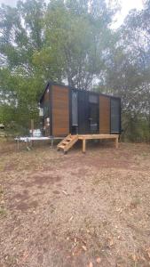 a tiny house sitting in a field next to trees at Hill Creek 3 Tiny House in Perwillowen