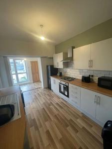 a kitchen with white cabinets and a wooden floor at The Castle - Grimsby/Cleethorpes perfect for Contractors in Grimsby