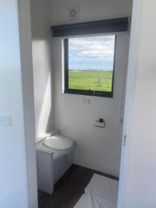 a small bathroom with a toilet and a window at Lough View Cabin in Rosebrook