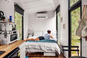 a woman sitting on a bed in a tiny house at Clarence Farm Stay in Maclean