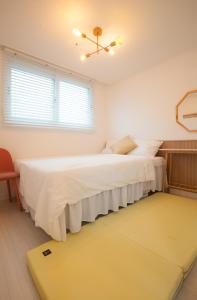 2 camas en un dormitorio blanco con alfombra amarilla en Seoul Station Joey N Ray house en Seúl