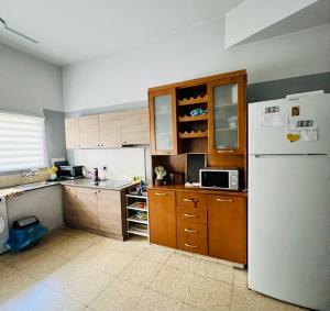 a kitchen with a white refrigerator and wooden cabinets at Past or Tail rooms in Larnaca