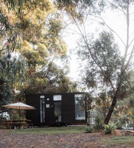a black tiny house with a picnic table and an umbrella at Djindarup Retreat 4 in Prevelly