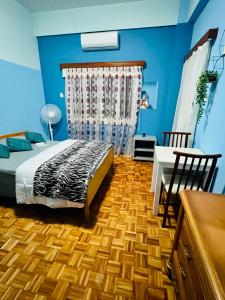a bedroom with a bed and a table and blue walls at Past or Tail rooms in Larnaka