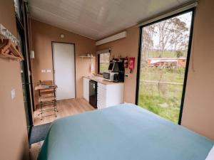 Habitación con cama y cocina con ventana en Streamside Tiny House, en Mangatarata