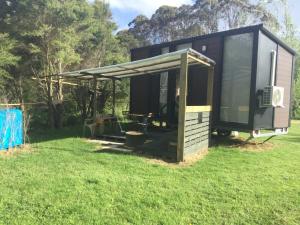 a tiny house with a canopy on a grass field at Streamside Tiny House in Mangatarata