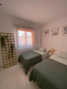 a bedroom with two beds and a window at Albatros Apartamentos Playa Granada in Motril