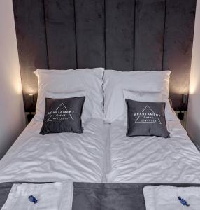 een bed met witte lakens en 2 kussens erop bij Apartament Sztuk Pięknych 4 in Piła