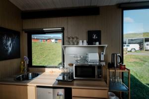 une cuisine avec un four micro-ondes et un évier ainsi qu'une fenêtre dans l'établissement Mighty Tiny House 2, à Ruawaro