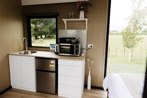uma cozinha com um micro-ondas, um lavatório e uma janela em Rural Delight em Ohaupo