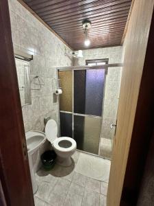 uma casa de banho com um WC e uma cabina de duche em vidro. em Hotel Halloween Inn Penedo em Penedo