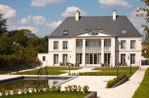 ein großes weißes Haus mit einem Teich davor in der Unterkunft La Ramade - Teritoria in Avranches