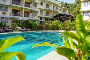 a swimming pool in front of a building at Indie Stays Goa in Candolim