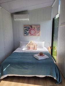 a bedroom with a large bed with a blue blanket at Deloraine Tiny Retreat in Whangarei