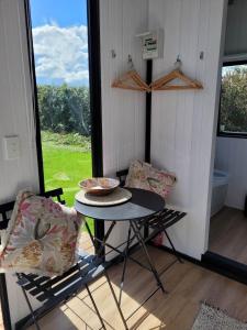 uma pequena mesa e cadeiras num quarto com uma janela em Deloraine Tiny Retreat em Whangarei