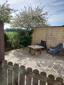 a wooden deck with a table and a bench at GITE LA BEAUTEE in Hermanville-sur-Mer