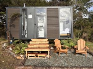 a tiny house with two chairs and a wooden table at Aroha Tiny House in Rangihaeata