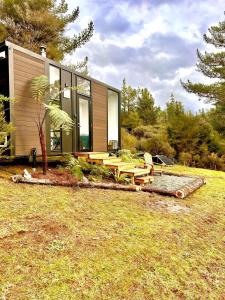 una pequeña casa con una mesa de picnic en un campo en Aroha Tiny House en Rangihaeata