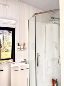 a white bathroom with a shower and a sink at Aroha Tiny House in Rangihaeata