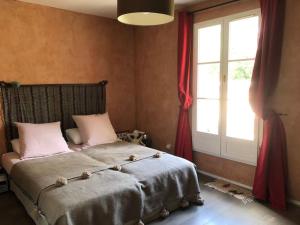 a bedroom with a bed with pink pillows and a window at Maison de ville avec jardin centre Montfort l'Amaury in Montfort-lʼAmaury