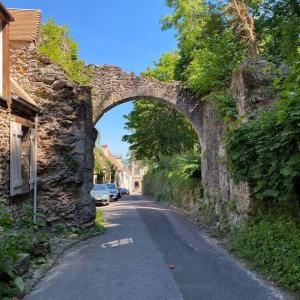 an old stone archway over a street with cars at Maison de ville avec jardin centre Montfort l'Amaury in Montfort-lʼAmaury