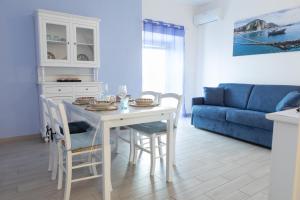 a white dining room table with chairs and a blue couch at Casa Di Circe Vista Mare - Centralissima, ad un passo da Tutto in Terracina