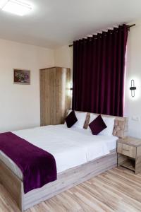 1 dormitorio con 1 cama blanca grande con sábanas moradas en TOURIST INN hotel, en Tashkent