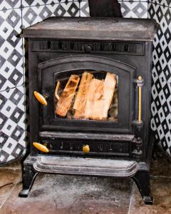 a stove with a pile of logs in it at Boss’s farmhouse in Valentia Island