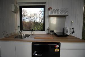 eine Küche mit einem schwarzen Kühlschrank und einer Spüle in der Unterkunft Breathe Inn in Kaitaia
