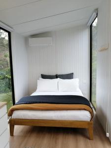 a bed in a room with a large window at Creekside at Kuaotunu in Matarangi
