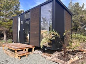 a black house with a wooden table and a bench at Ruru Tiny House in Rangihaeata