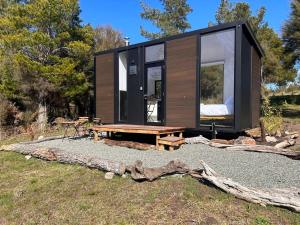 a tiny house with a bench and a table at Ruru Tiny House in Rangihaeata