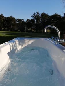 a bath tub filled with water with a faucet at Creekside at Kuaotunu in Matarangi