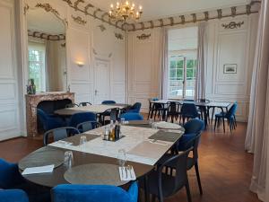 una sala da pranzo con tavoli, sedie e lampadario a braccio di Château du Haut-Neubois a Spa