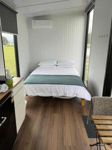 a bedroom with a bed and a large window at Rangiuru Stream Tiny home in Otaki Beach