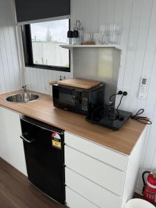 a small kitchen with a microwave and a sink at Rangiuru Stream Tiny home in Otaki Beach