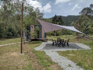 a picnic table and chairs under a white tent at Sungai Tiny House 2 in Raub