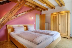 ein Schlafzimmer mit einem großen Bett mit einer rosa Wand in der Unterkunft Obst- Ferienhof Ragg in Immenstaad am Bodensee