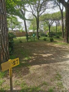 un cartel en un parque junto a un árbol en Holiday Center Valdor, en Cavallino-Treporti