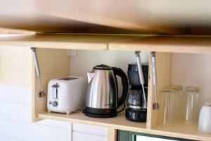 a shelf with a coffee maker and appliances on it at Bostebacken Gard Tiny House in Eckerud