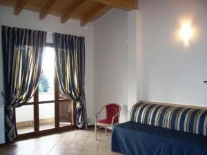 a bedroom with a bed and a chair and a window at Villa Giovanna in Somma Lombardo