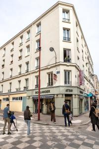 eine Gruppe von Menschen, die vor einem Gebäude eine Straße überqueren in der Unterkunft Appartement cosy et équipé proche paris in Le Pré-Saint-Gervais