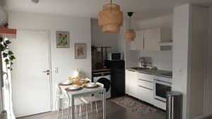 Una cocina con una mesa pequeña y una cocina con gabinetes blancos. en Charmant appartement cosy et paisible proche Paris - métro à 2min, en Romainville