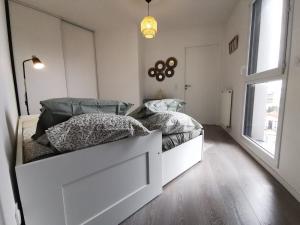 Una habitación blanca con una cama y una ventana en Charmant appartement cosy et paisible proche Paris - métro à 2min, en Romainville