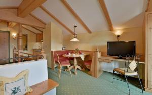 a living room with a television and a table and chairs at Landhaus Schwentner in Kössen