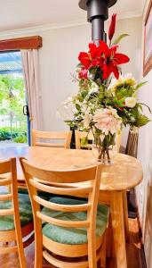 a wooden table with a vase of flowers on it at Snowy Valleys iconic stay - Moonshiner Cottage @ Distillery in Tumbarumba