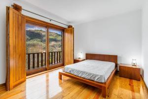 um quarto com uma cama e uma grande janela em Casa do Fijogo - Family friendly Villa with a Private Pool em Rio Caldo