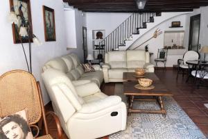 una sala de estar con muebles blancos y una escalera. en Ca la Trini - turisme rural, en Torrelles de Foix