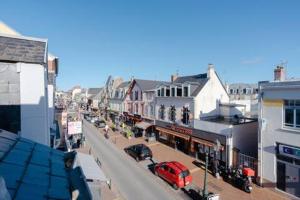 a city street with cars parked on the street at Le Balbec in Cabourg
