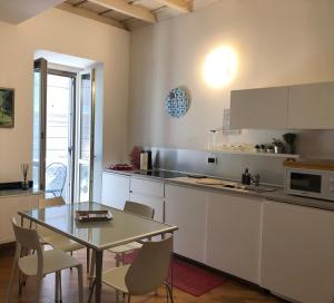 una cocina con armarios blancos y una mesa con sillas. en Emma Home adiacente alla Piazza Ducale, en Vigevano
